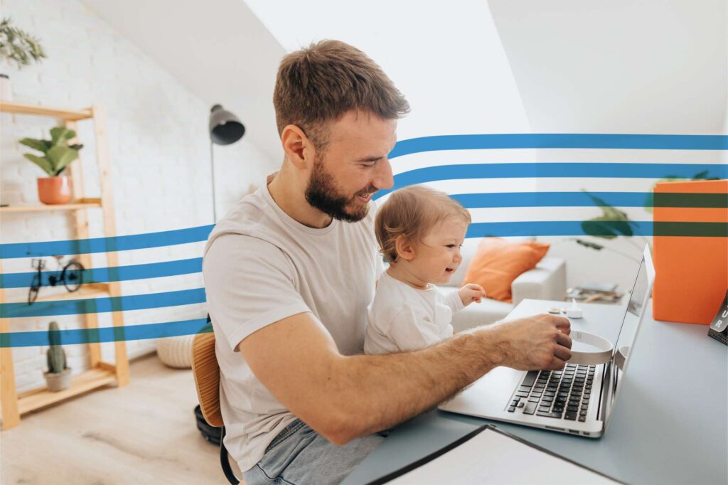 Father and toddler working together on a laptop at a bright home office with blue striped wall decor