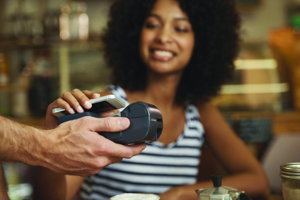 Closeup shot of a woman paying by using her smart phone and a point of sale machine